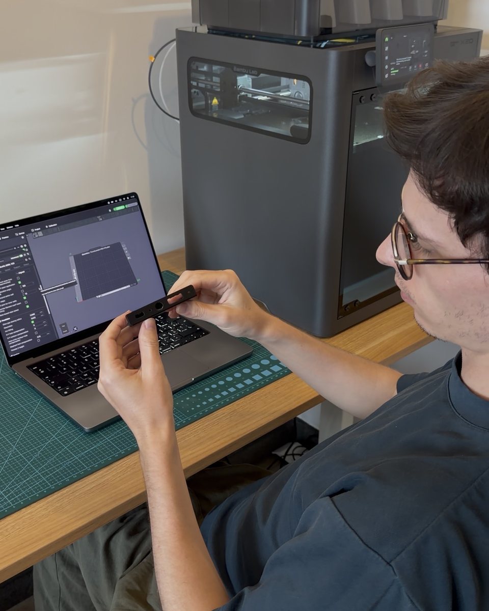 Yoann at the bench, working on a laptop next to a 3D printer.