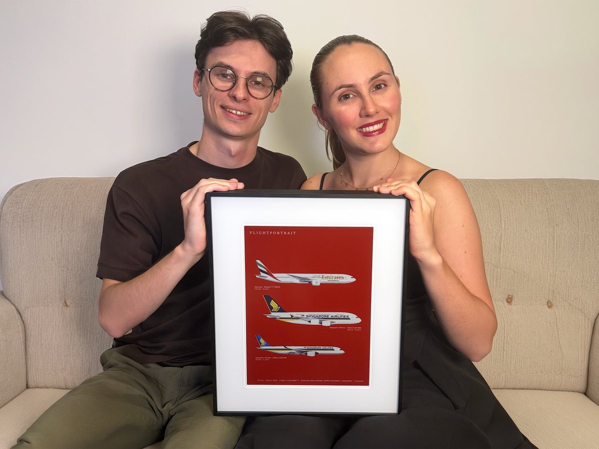 Audrey and Yoann on a sofa, holding a FlightPortrait drawn on red.